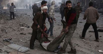 Dos sirios trasladan este viernes a una víctima de un bombardeo en las afueras de Damasco.