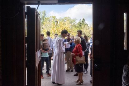 Un asistente ayuda a administrar la comunión a los feligreses que se quedaron fuera de la parroquia el domingo pasado.