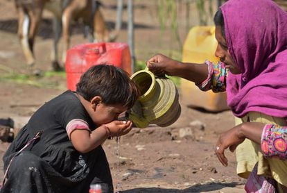 Una madre ayuda a su hija a beber agua en un asentamiento en Peshawar (Pakistán), el 22 de marzo de 2016.