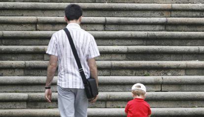 Un padre con su hijo de espaldas ante unas escaleras.