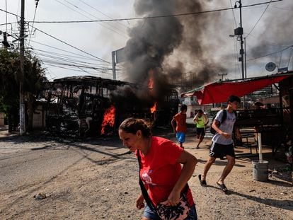 Personas corren al lado de un camión que fue incendiado en Acapulco, Guerrero.