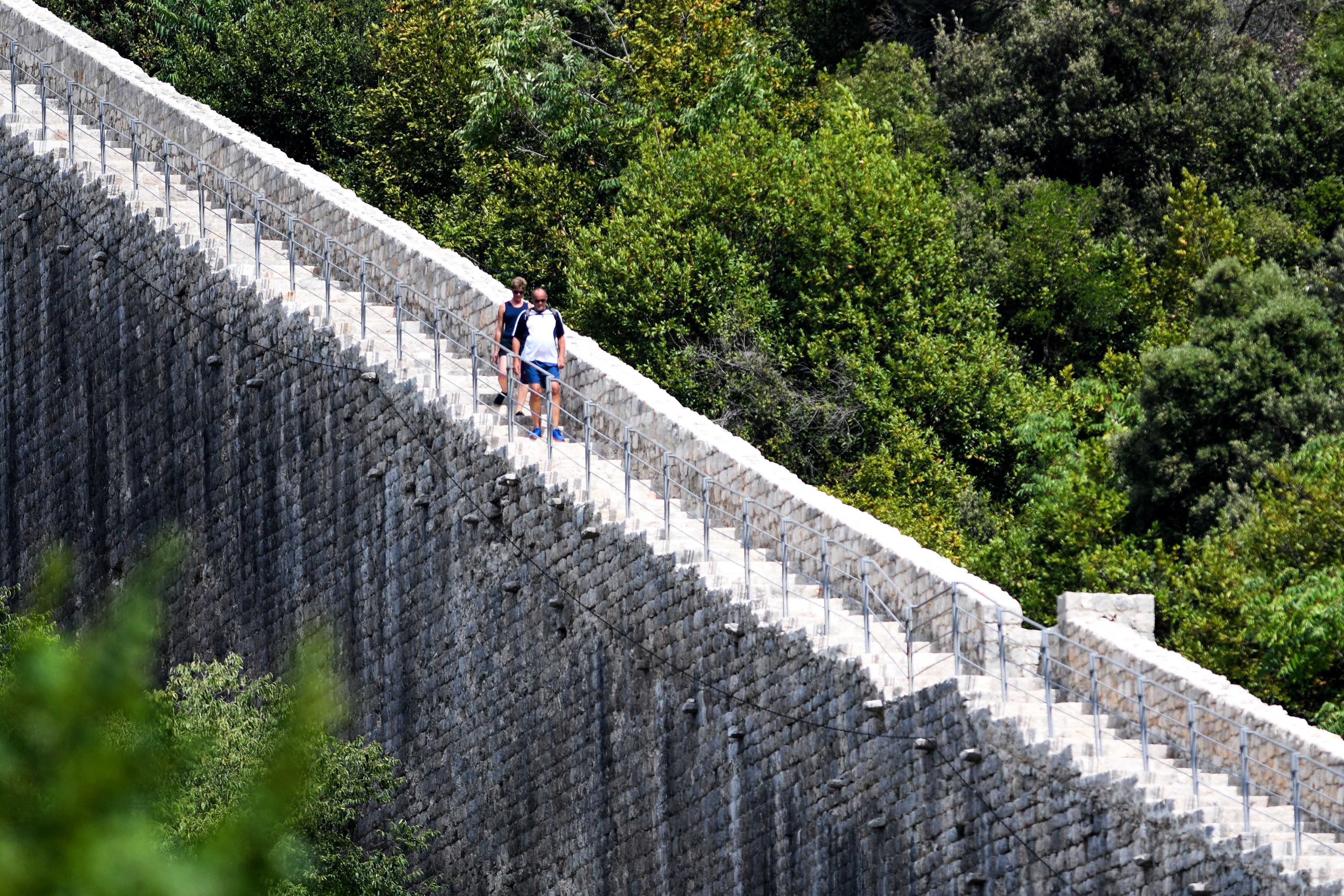 Turistas caminan a lo largo de las murallas de Ston.