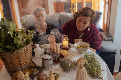 Pepa Amaya (a la izquierda) quema incienso junto a algunas de las hierbas con las que elabora un alcohol que regala como remedio natural. Junto a ella, su amiga María Jesús Fernández.