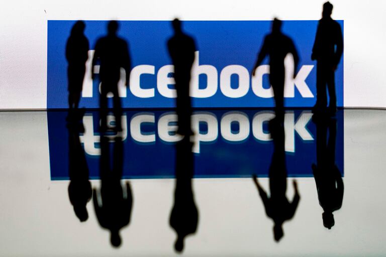 Varias personas ante un logo de Facebook, en febrero pasado.