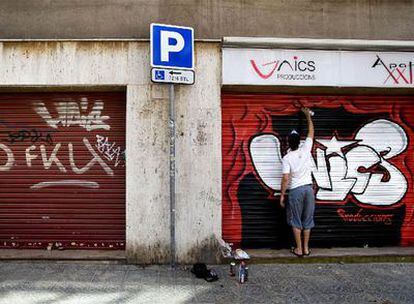 La persiana metálica pintarrajeada de la izquierda contrasta con la que decora un <i>grafitero </i>a la derecha.