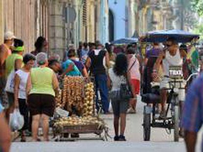 Dos cuentapropistas cubanos, un vendedor de productos agropecuarios (i) y un "Bicitaxi" (d), se movilizan por las calles de La Habana (Cuba).