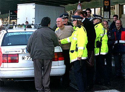 Un taxista, de espaldas, dialogaba con un miembro de un piquete delante de la Policía Municipal en el aeropuerto de Barajas.