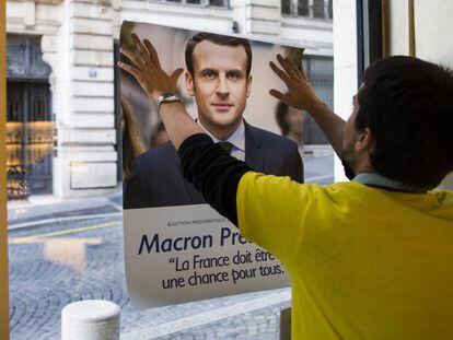 Un votante coloca un cártel de apoyo a Emmanuel Macron.