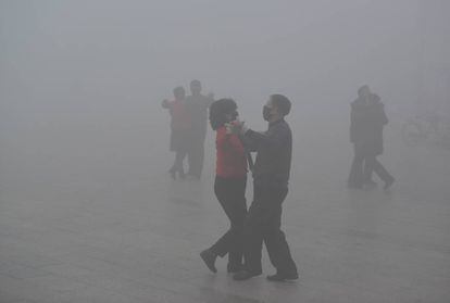 Bailarines en una plaza china en un día de contaminación.