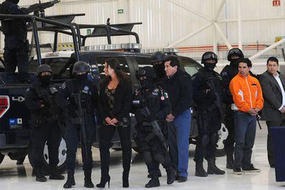 El supuesto narco Harold Mauricio Poveda, alias <i>El Conejo</i> (con chándal naranja), y su novia, Juliana López, son mostrados por la policía tras su detención, el viernes en Ciudad de México.