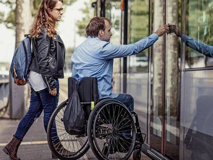 Un joven pasea en silla de ruedas con su compañera. 