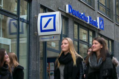 Un grupo de j&oacute;venes pasea frente a una sucursal de Deutsche Bank en Hamburgo (Alemania).