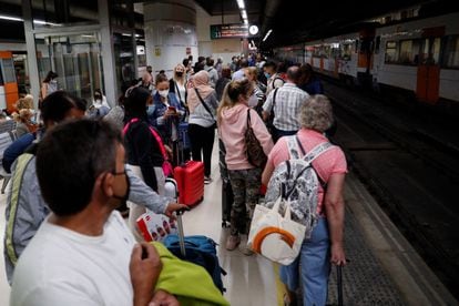 Decenas de pasajeros esperan en la estación de Sants de Barcelona la llegada de un tren.