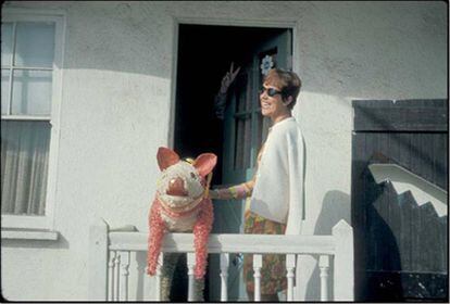 Phyllis Gebauer, con la piñata de cerdo y la mano de Thomas Pynchon asomando detrás de la puerta haciendo el signo de la paz. Fotografía tomada en California en 1965.