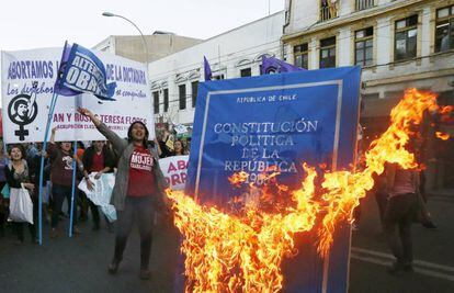 Manifestantes queman una imagen de la Constitución de Chile.