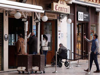 Varias personas esperan a ser atendidas, este jueves en el exterior de una cafetería de Málaga.