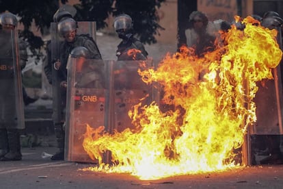 Miembros de la Guardia Nacional Bolivariana (GNB) se protegen del fuego en medio de las protestas en Caracas, en junio de 2017.
