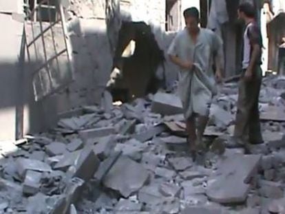 Fotograma de un vídeo facilitado por la oposición que muestra a dos hombres caminando sobre los escombros en la calle de una zona de Alepo.