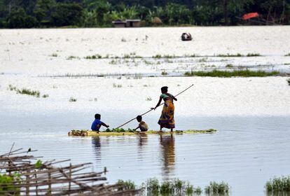 Un mujer y sus hijos cruzan en una balsa por una de las zonas afectadas por las inundaciones en el distrito de Morigaon, Estado de Assam, India.