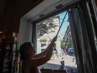 Una empleada de una librería de Madrid cierra las cortinas del escaparate, este martes.