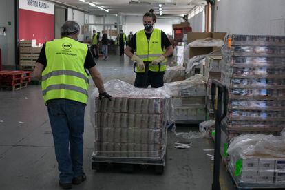 Dos voluntarios colocan productos en un almacén del Banco de Alimentos. 
