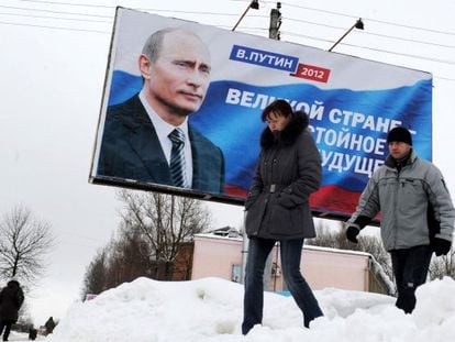 Dos personas frente a un cartel de Vladimir Putin en Mosc&uacute;.