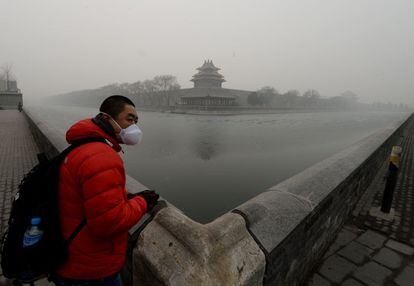 Un turista chino provisto de mascarilla para paliar los efectos nocivos de la contaminación, visita los alrededorres de la ciudad prohibida en Pekín.