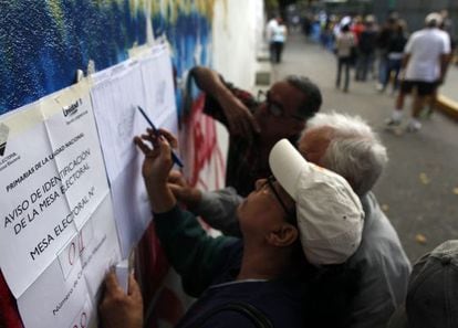 Un grupo de electores buscan en las listas d&oacute;nde les toca votar en Caracas.