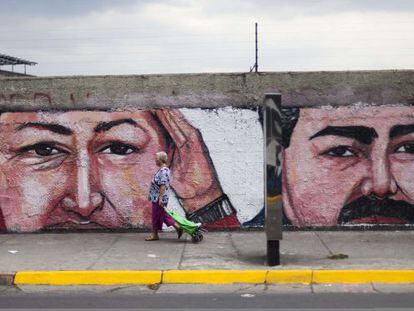 Una mujer pasa frente a un muro con una pintada de Ch&aacute;vez y Maduro.