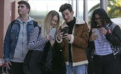 Un grupo de jóvenes miran sus móviles. 