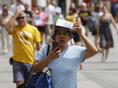 Una mujer se protege del sol mientras camina por una calle de Madrid este miércoles. España atraviesa estos días la que es, de momento, su peor ola de calor del verano.