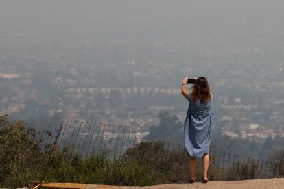 Una mujer toma una fotografía a la ciudad de Santiago cubierta por una nube de humo.