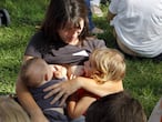 Una madre da de mamar a dos niños.