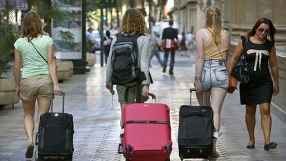 Tres j&oacute;venes por las calles de Valencia con su futuro incierto en la maleta.