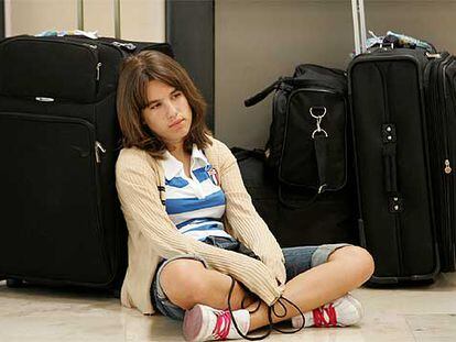 Una joven espera con sus maletas en el aeropuerto de Barajas (Madrid).