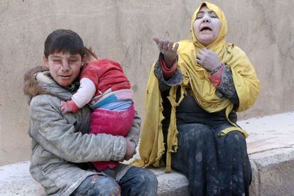 Una mujer, un niño y un bebé, cubierto de polvo, en estado de shock después del ataque ataque aéreo. Mientras las partes en conflicto de Siria comenzaron lo que se espera que sea una última jornada decisiva de negociaciones en Ginebra, en medio de advertencias de que al menos deben acordar una agenda para salvar el proceso.