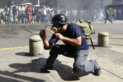 Un manifestante contrario al gobierno se dispone a disparar su tirachinas.