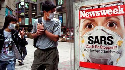Transeúntes en Hong Kong con mascarillas para protegerse contra la neumonía atípica miran un anuncio de la portada de la revista <i>Newsweek</i> dedicada a la epidemia<i>.</i>