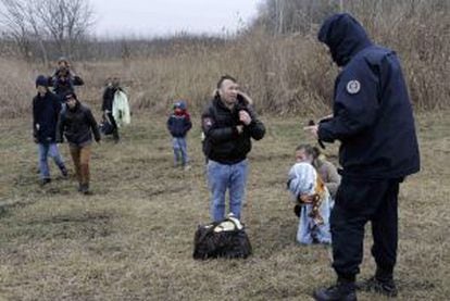Un policía serbio pide la documentación a varios kosovares que tratan de cruzar la frontera con Hungría a pie, el 6 de febrero.