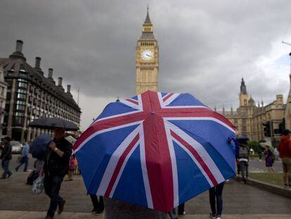 Una persona pasea en las inmediaciones del Parlamento Brit&aacute;nico con la bandera de Reino Unido.