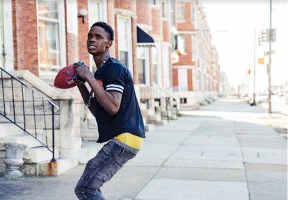 Un vecino del West Baltimore juega con la pelota de fútbol americano de un niño.