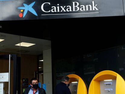 Clientes de CaixaBank en la puerta de una sucursal de la entidad financiera en Madrid.