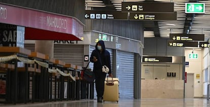 Un pasajero camina por el aeropuerto de Barajas entre tiendas y bares cerrados.