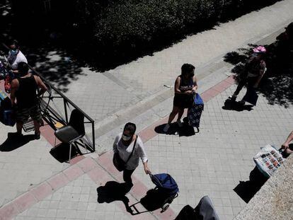 Colas de personas esperan a las puertas de la Parroquia Santa María Micaela para recibir ayuda alimentaria.