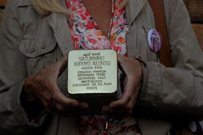 Una mujer sostiene la 'stolpersteine' de Saturnino Arroyo antes de colocarla delante de su portal.