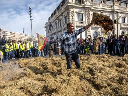 Un agricultor pega fuego este jueves a un montón de paja del arroz frente al edificio del Reloj, a la entrada del puerto de Valencia, durante la tractorada convocada por varias organizaciones agrarias.