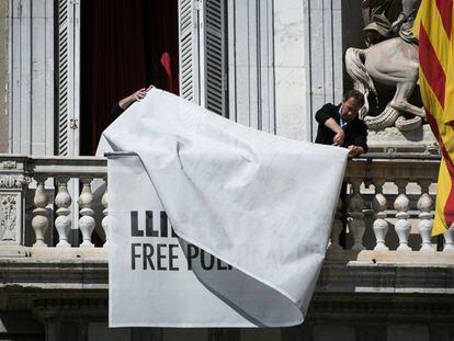 Treballadors del palau de la Generalitat retiren les pancartes a favor dels presos del balcó de l'edifici.