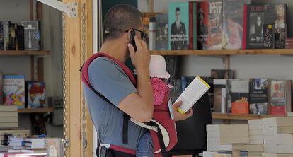 Un hombre pasea con su beb&eacute; en la Feria del Libro de Valencia.