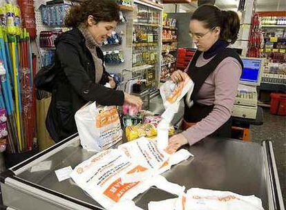 Una clienta y una cajera en un supermercado de L&#39;Hospitalet de Llobregat metiendo la compra en bolsas de plástico, ayer.