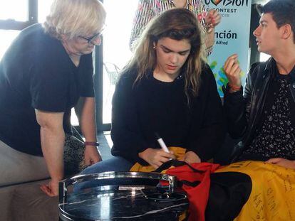 Amaia y Alfred firman en una bandera española con toro.